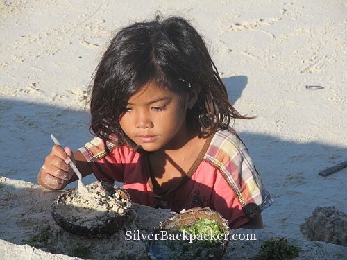 Girl playing with sand and seaweed Caluya