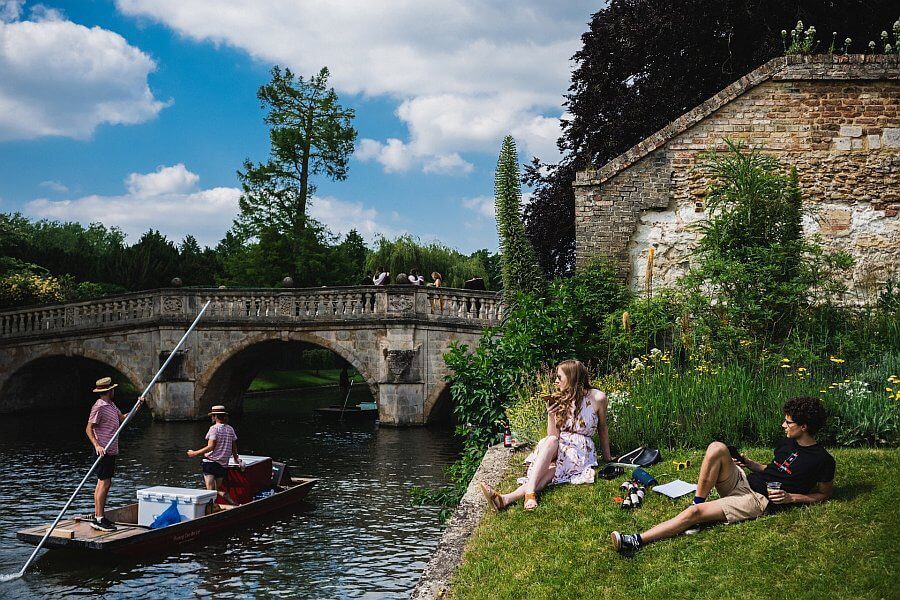 cambridge punting on the river cam with students relaxing on the bank