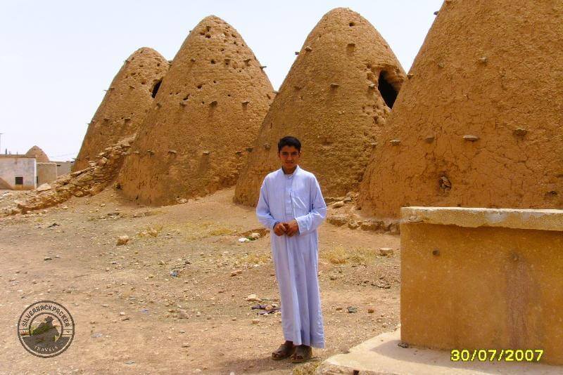 a teenage boy standing by beehive houses